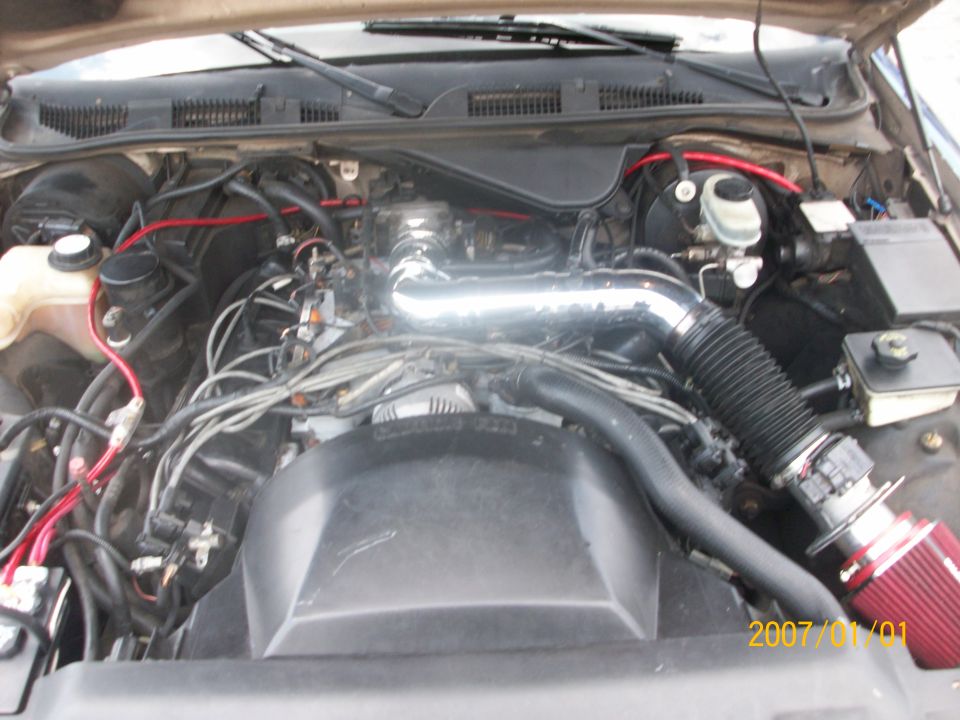 Engine bay with chrome intake tube, red cone filter, and red plug wires
