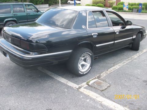 1993 Mercury Grand Marquis - A black 1993 Mercury Grand Marquis is parked in a lot next to a green SUV.
