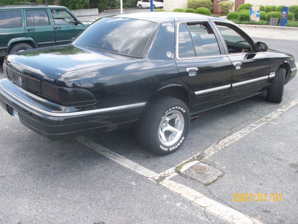 Black Mercury Grand Marquis sedan, rear 3/4 view, in parking lot