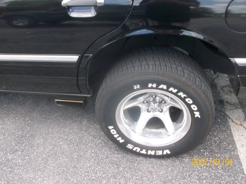 1993 Mercury Grand Marquis - The rear side of a black sedan is shown, focusing on the wheel and tire assembly.