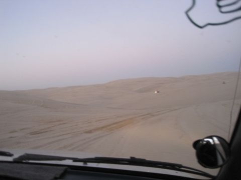 1989 Toyota Pickup/SR5 - Driving through vast sand dunes with another vehicle in the distance under a hazy sky.