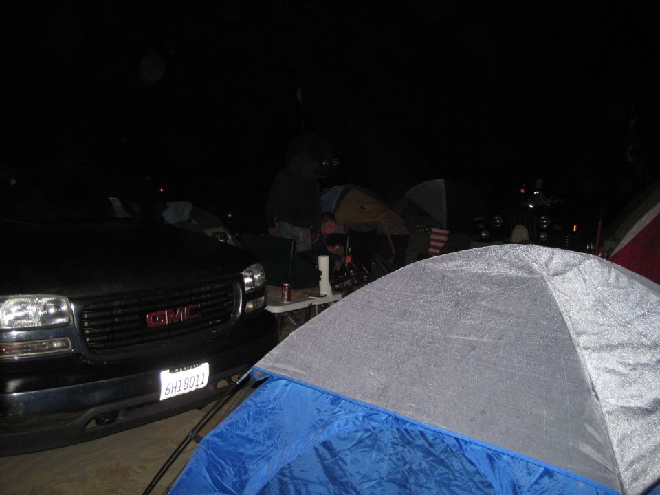 Black GMC truck front end with license plate 6H18012 at a campsite