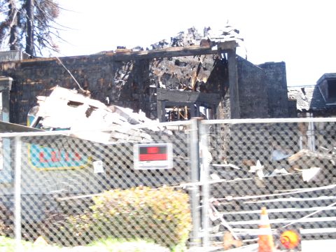 1989 Toyota Pickup/SR5 - A fire has severely damaged a building, leaving behind charred remains and debris, with a fence in front.