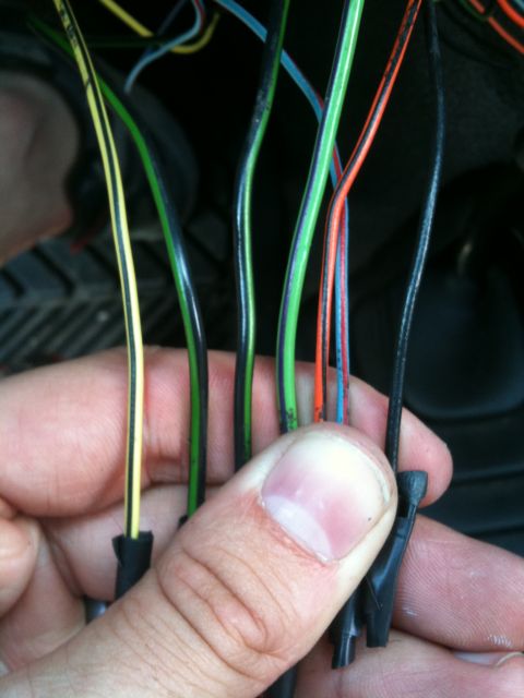 1994 Ford Bronco - Close-up of a vehicle's wiring harness, showing various colored wires being held by a hand.