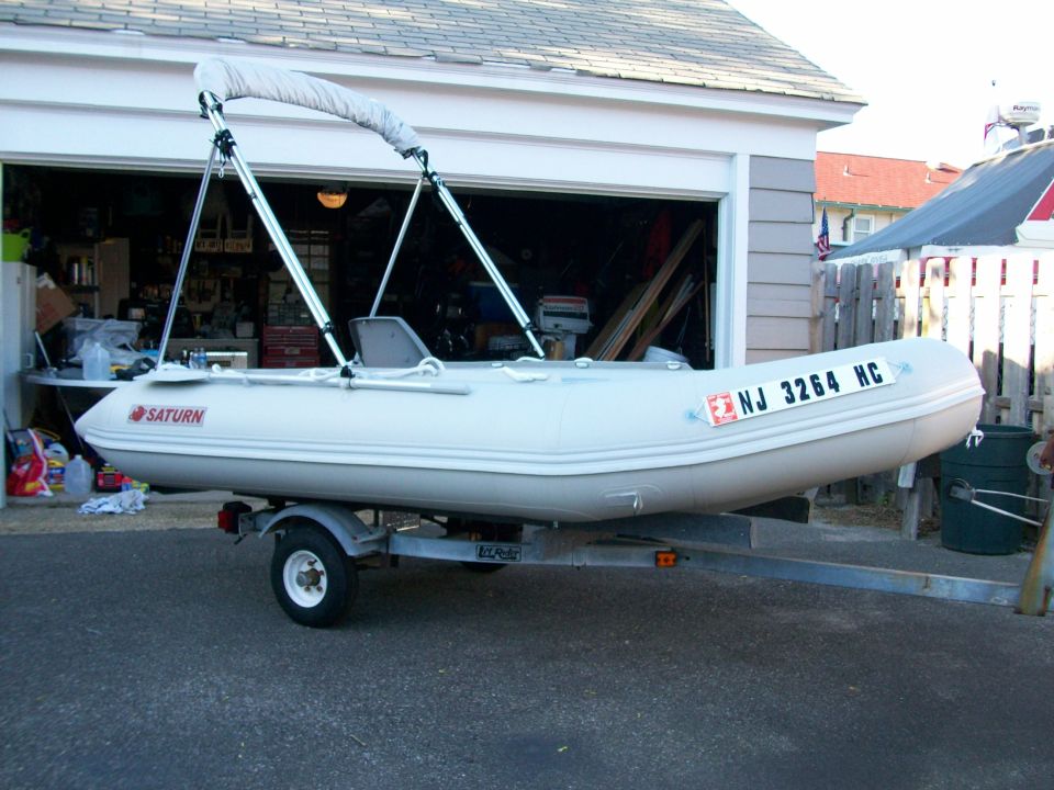 Gray Saturn inflatable boat with bimini top on a single-axle trailer in a driveway