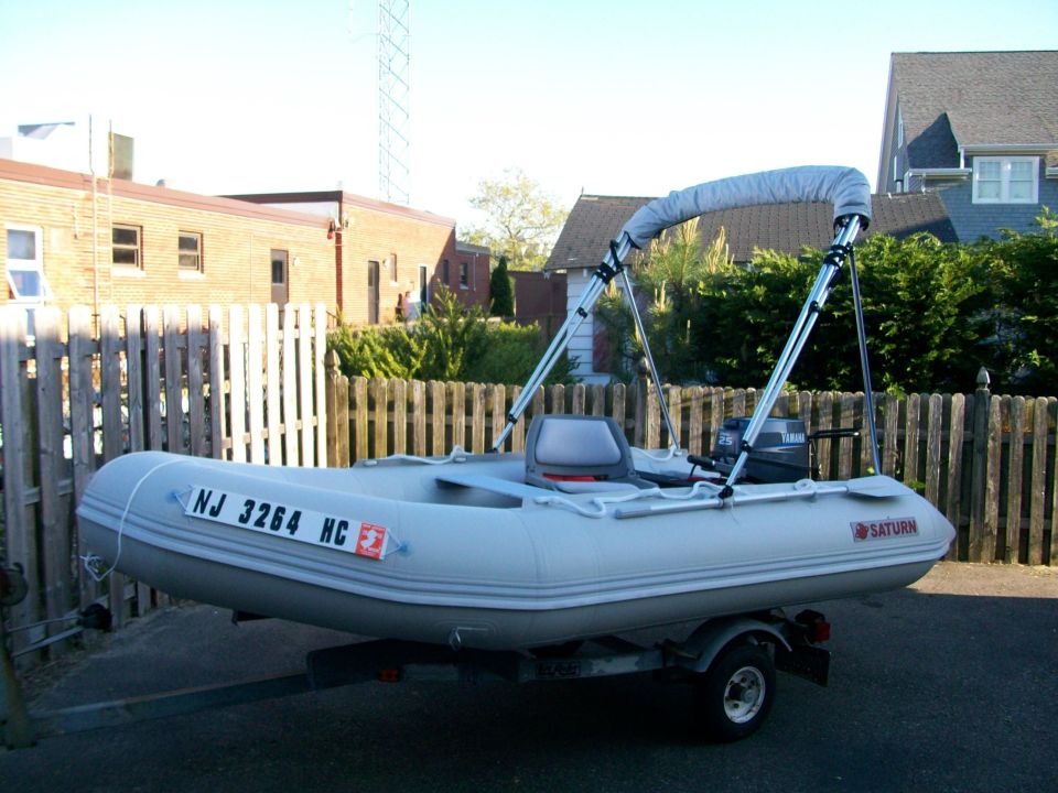 Gray Saturn inflatable dinghy with Yamaha 25 outboard on a trailer in a driveway