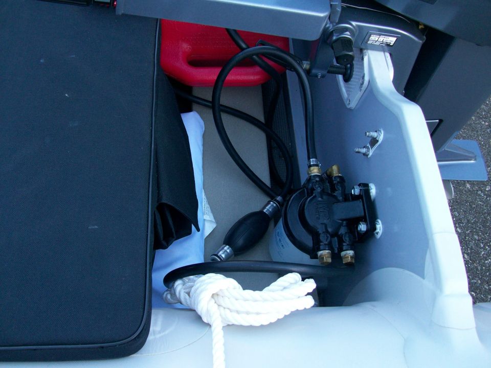 Fuel filter, primer bulb line and red gas tank on an inflatable boat transom with dock line