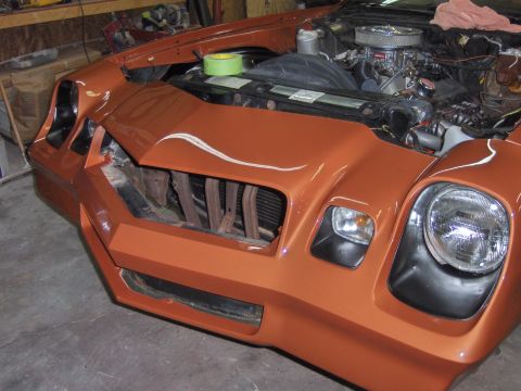 1980 Chevrolet Camaro - Front view of an orange Chevrolet Camaro undergoing repairs, with the hood open and grille missing.