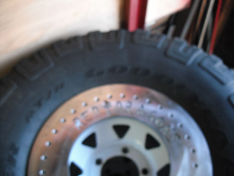 Close-up of a tire with a beadlock wheel. Text on wheel is partially visible