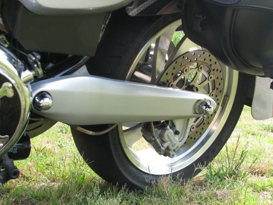 Motorcycle rear wheel with drilled rotor, Brembo caliper and alloy swingarm on grass
