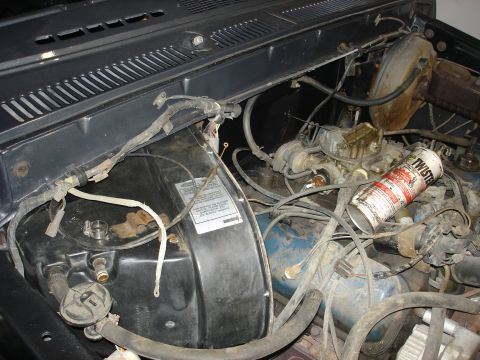 1979 Ford F-250 - Close-up view of a cluttered engine bay, showing various mechanical components and a can of cleaner.