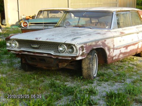 1963 Ford Galaxie - Two vintage cars, including a 1963 Ford Galaxie, sit in a grassy area with a building in the background.