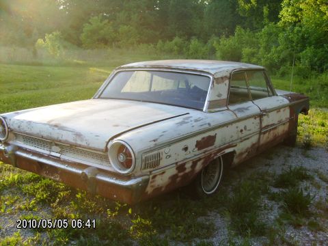 1963 Ford Galaxie - This weathered 1960 Ford Galaxie shows significant rust and paint deterioration, captured in a three-quarter front view.