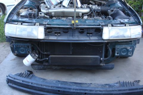 1993 Ford Taurus - The front bumper and grille are removed, exposing the engine and cooling system of a green vehicle.