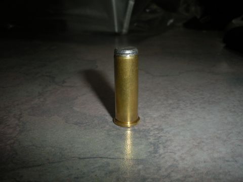 1996 Ford Bronco - A single bullet casing rests on a textured surface, casting a shadow.