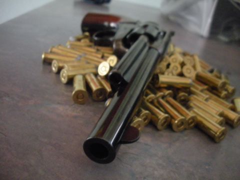 1996 Ford Bronco - A handgun rests on a collection of brass shell casings on a wooden surface.
