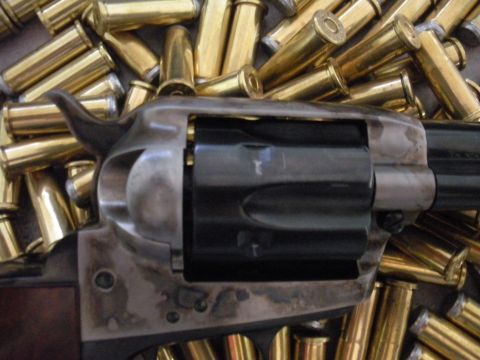 1996 Ford Bronco - Close-up of a revolver's cylinder and frame surrounded by numerous brass cartridges. The SuperMotors.net logo is in the lower right corner.