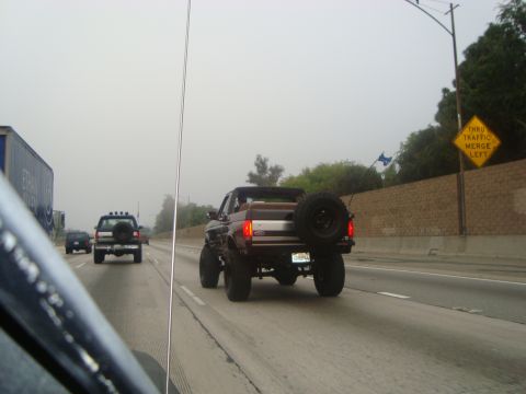 1986 Ford Bronco - A lifted Ford Bronco with a spare tire is seen driving on the highway.