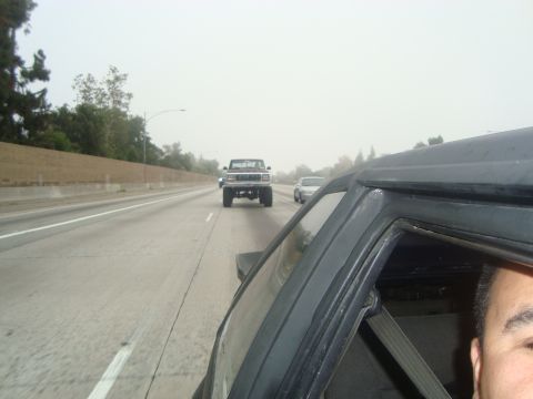 1986 Ford Bronco - A Ford Bronco is seen driving on a highway, with another vehicle in the foreground.