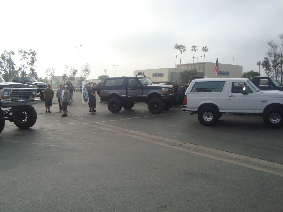 Lifted 1987-1991 Ford Bronco parked next to a white 1987-1991 Ford Bronco and a lifted older Ford truck
