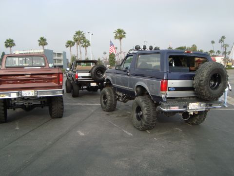 1986 Ford Bronco - A blue Ford Bronco, likely a 1987 model, is parked alongside two Ford pickup trucks.