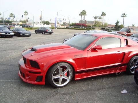 1986 Ford Bronco - This red Ford Mustang, likely from the mid-2000s, is parked in a lot with other vehicles.