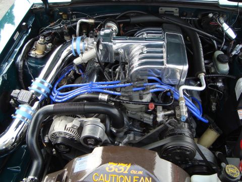 1986 Ford Bronco - Engine bay details a chrome intake manifold and blue spark plug wires. The fan shroud indicates a 351 cubic inch engine.