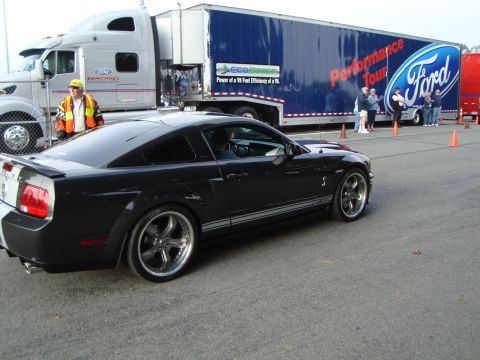 1986 Ford Bronco - A black 2007 Ford Mustang Shelby GT500 is seen next to a Ford Performance Tour trailer.