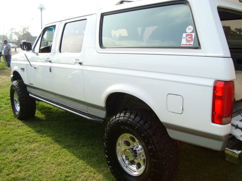 1986 Ford Bronco - This lifted SUV is shown from the rear quarter panel, highlighting its large tires and side running boards.