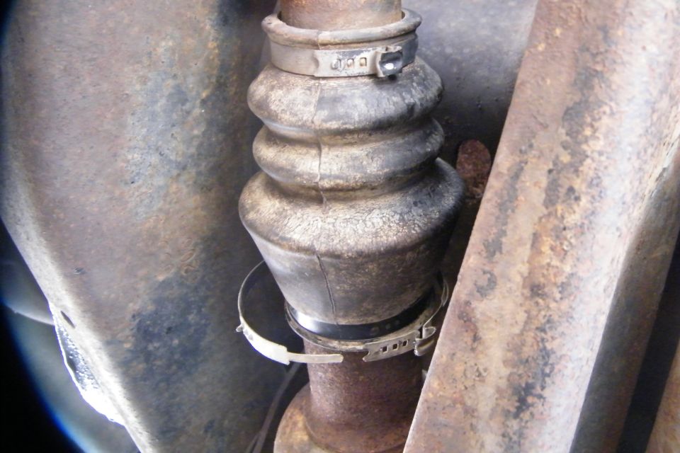 Now that all that is gone, time to remove the axle.  When on the drivers side, just slide the axle out...easy now.  The passenger side's axle is longer, and it connects to a CV joint before dissapering in the diff.  Climb under and remove the two clips and slide the boot one way.  NOW, you can easily pull the axle out.  I had my wife do it while I was under guidling the axle out.  Now there's nothing guiding it or stopping it from draging along the arm...  If you're carefull, you can use the clips later.