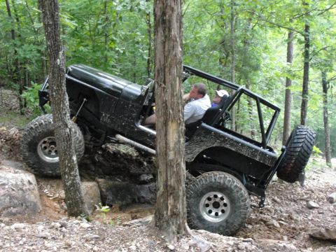 1967 Ford Mustang - Off-road Jeep Wrangler tackling a challenging rocky trail in the woods.