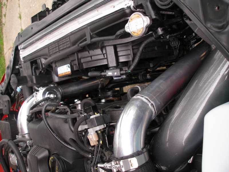Engine bay with custom intake piping. Radiator cap visible