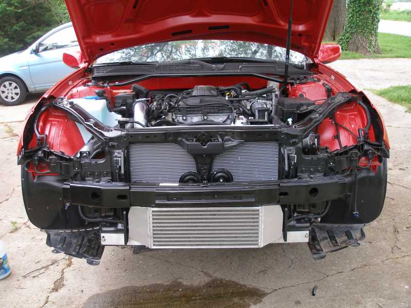 Red coupe with bumper removed showing polished front-mount intercooler below radiator