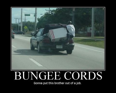 1989 Ford Bronco - A person rides atop a box secured to a car's trunk with bungee cords.