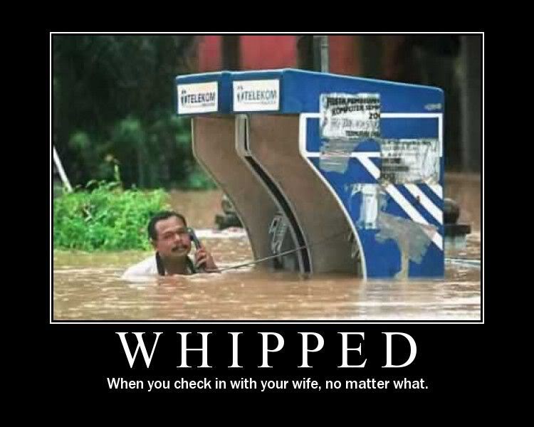 Man in floodwaters holding a phone, with a blue Telekom structure partially submerged