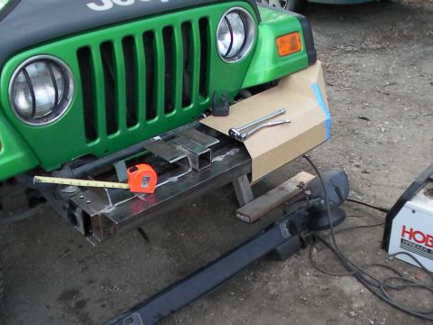1987 Suzuki Samurai - Custom bumper fabrication in progress on a green Jeep, with welding gear and measuring tools nearby.