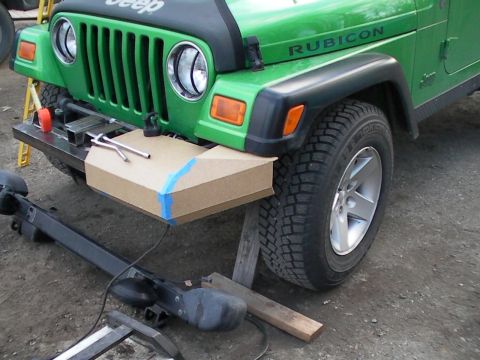 1987 Suzuki Samurai - A Jeep Wrangler's front bumper is undergoing modification, with a cardboard template and tools laid out.