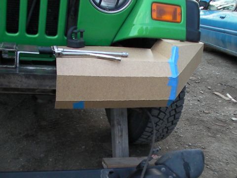 1987 Suzuki Samurai - A cardboard mockup of a custom bumper is being fitted to a green Jeep, with tools laid out on top.