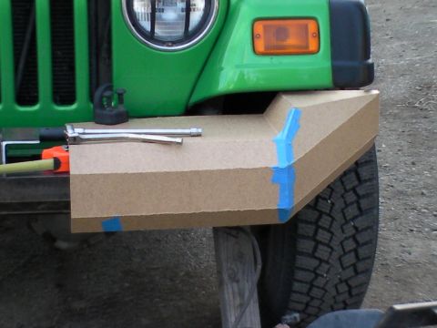 1987 Suzuki Samurai - A cardboard mockup is being fitted to the front bumper of a green Jeep, with tools laid out.
