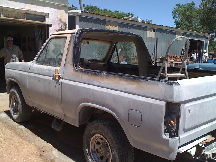 Gray primered Ford Bronco with top removed in a yard