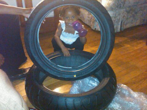 1991 Ford Crown Victoria LTD - A child looks through a tire while another tire sits below it.