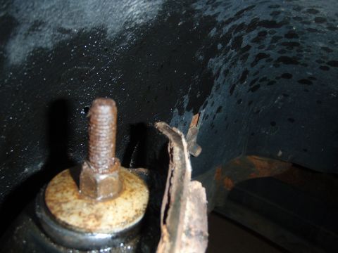 1995 Ford Bronco - A close-up view shows a rusty bolt and a damaged metal bracket, suggesting wear and tear on a vehicle component.