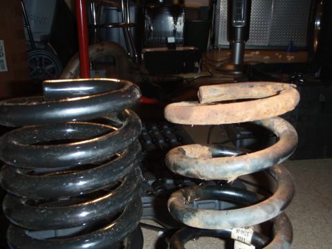 1995 Ford Bronco - Comparison of a new coil spring next to a heavily rusted old one, likely for a vehicle suspension system.