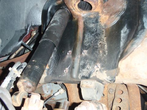 1995 Ford Bronco - Detail of vehicle suspension parts, showing rust and wear on the shock absorber and mounting bracket.