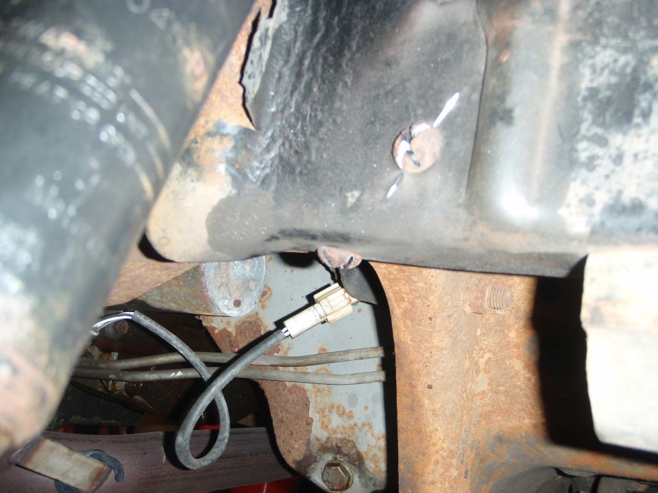 Undercarriage of a vehicle with rusty metal frame, a wire harness, and a Supermotors.net logo