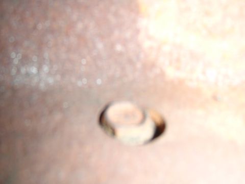 1995 Ford Bronco - Close-up of a rusty metal surface with a bolt head, likely a vehicle part.