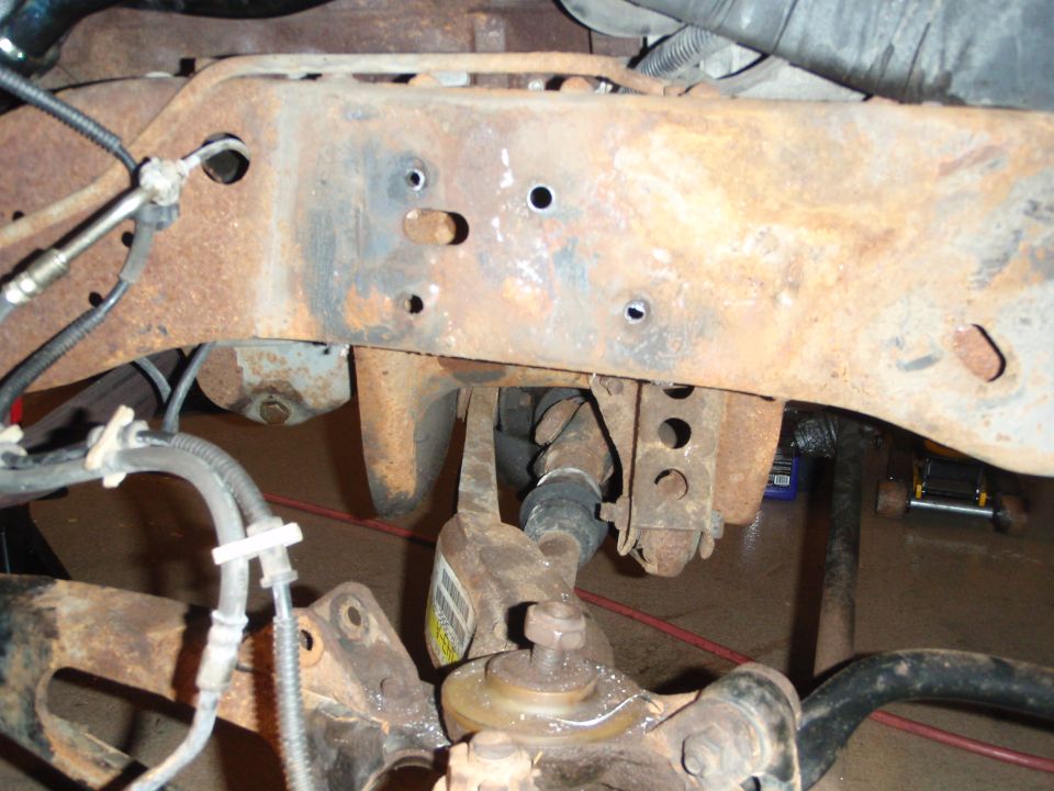 Close-up of heavily rusted vehicle frame with suspension components visible