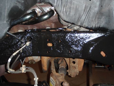 1995 Ford Bronco - Close-up view of a vehicle's undercarriage, showing the frame, engine, and drivetrain components.