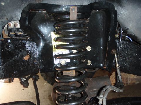 1995 Ford Bronco - This image shows a close-up view of a vehicle's front suspension system, focusing on the coil spring and its mounting bracket.