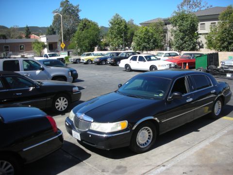 2004 Ford Crown Victoria - A black Lincoln Town Car is parked in a lot with other vehicles.